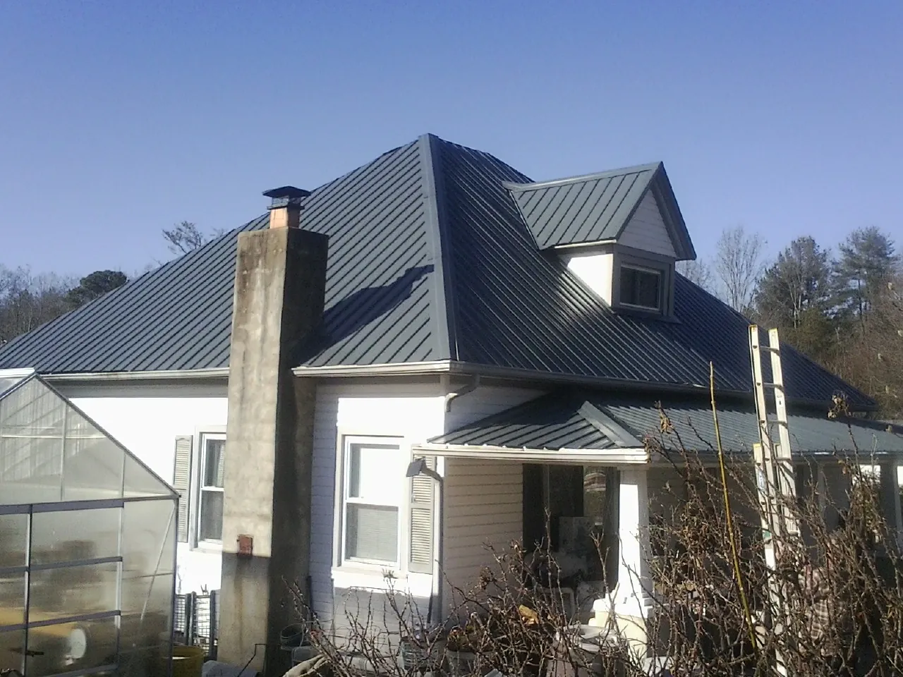 Dark blue standing seam metal roof on a white farmhouse with dormer — Slate & Tile Roof Repair by Roofing Brothers in Decaturville