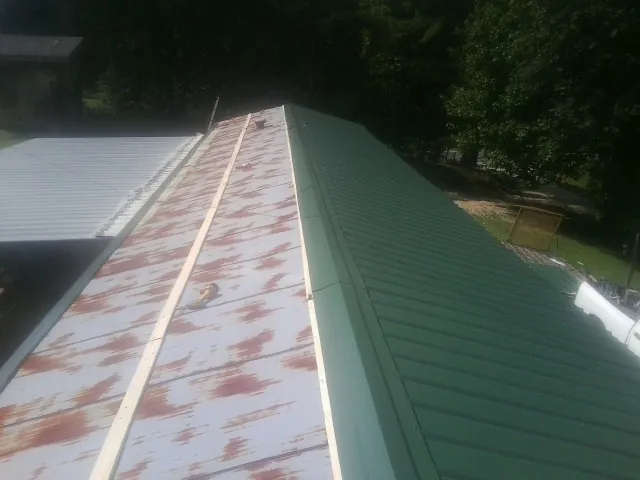 Old rusted panels beside newly installed green metal roofing — Wind Damage Roof Repair by Roofing Brothers in Decaturville