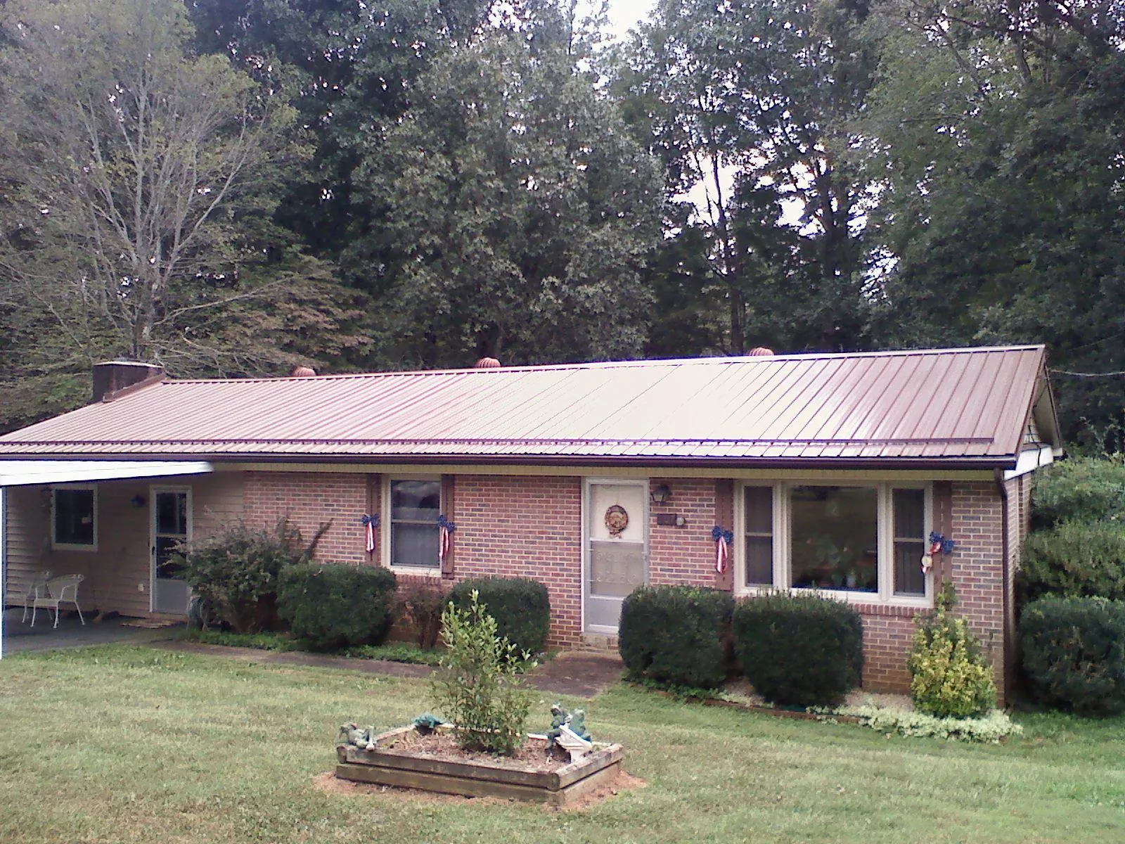 Bronze metal roof on a brick ranch home with a carport in Decaturville