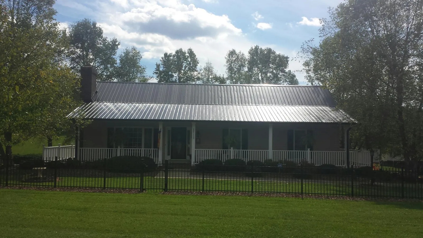 Gray metal roof on a brick ranch with a full width front porch — Gutter Guard Installation work by our crew in Decaturville