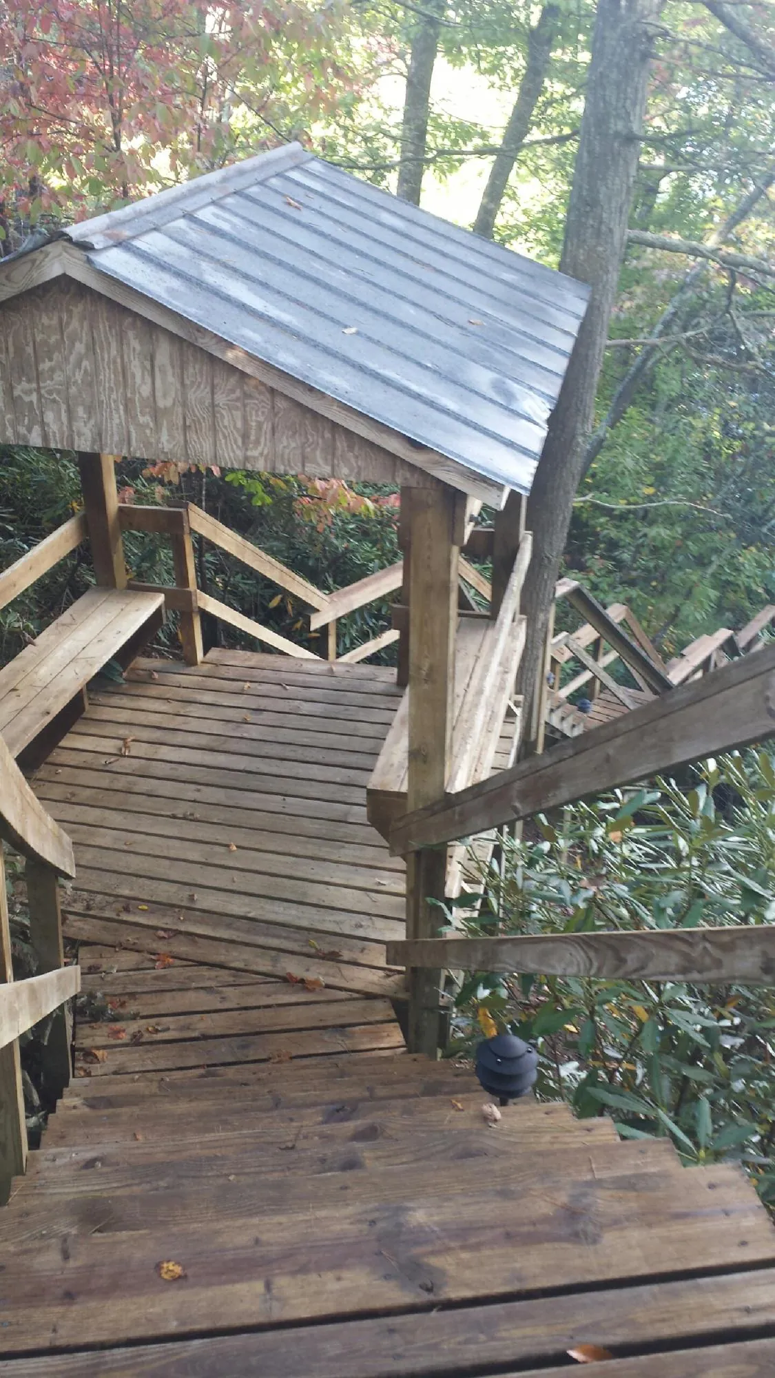 Metal roofed shelter over wooden steps on a wooded walkway — Skylight Repair & Installation work by our crew in Decaturville