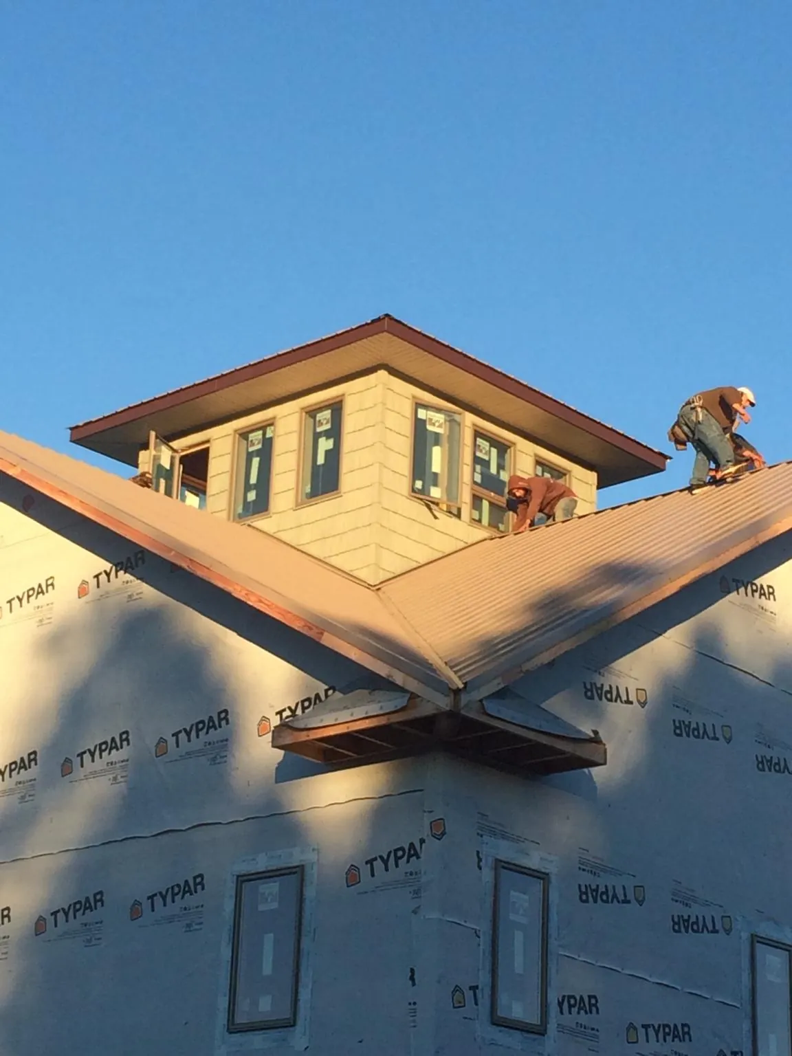 Roofers working around a rooftop cupola on a new metal roof at sunset — Roof Waterproofing in Decaturville by Roofing Brothers